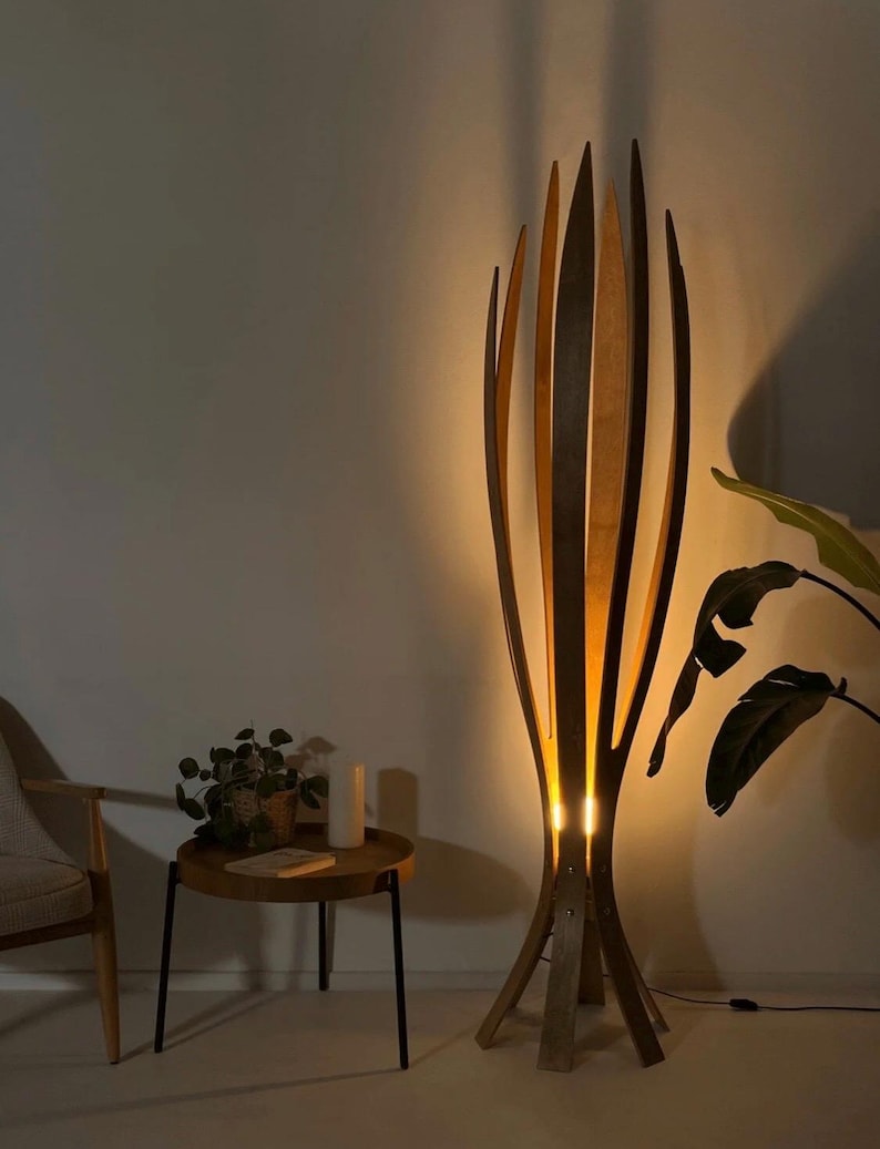 May include: A tall, wooden floor lamp with a unique design. The lamp features vertical, curved wooden slats that create an open, organic shape. The warm light shines through the slats, creating a cozy ambiance. The lamp is a decorative lighting fixture.