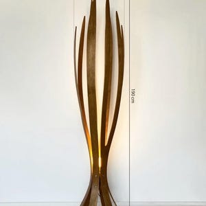 May include: A tall, wooden floor lamp with a unique, organic design. The lamp is approximately 75 inches tall and 16 inches wide, featuring vertical wooden slats that curve upwards. The lamp's base is 16 inches wide. The lamp emits a warm, inviting glow.