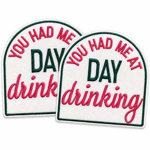 May include: Two arched embroidered patches with a white background and a dark green border. The text reads YOU HAD ME AT DAY drinking in a combination of pink and dark green thread, with the word DAY in green and the rest in pink.