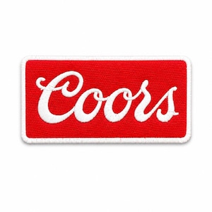 May include: A rectangular embroidered patch featuring a vibrant red background with the word Coors stitched in white cursive script. The patch is finished with a thick white stitched border that frames the entire rectangular design.