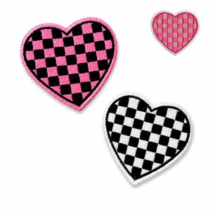 Op de afbeelding: Drie hartvormige patches met een dambordpatroon. Eén patch heeft een roze rand en een zwart-roze dambordontwerp. Een andere heeft een witte rand en een zwart-wit dambordontwerp. Een derde heeft een roze rand en een roze-grijs dambordontwerp.