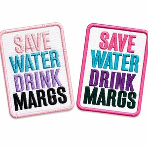 May include: Two rectangular embroidered patches with white backgrounds and pink borders. The text reads SAVE WATER DRINK MARGS in stacked lines. The left patch has light pink, blue, purple, and black text. The right patch has pink, blue, purple, and dark green text.
