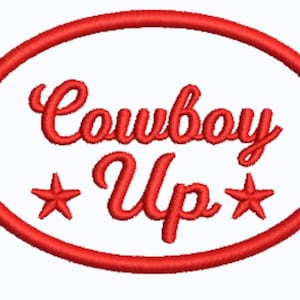 May include: A red embroidered patch featuring an oval border. Inside the oval, the text "Cowboy Up" is written in a cursive script. Two five-pointed stars are positioned on either side of the word "Up" within the red stitched oval frame.