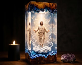 Könnte beinhalten: Eine rechteckige Lampe aus Harz und Holz mit einer zentralen Jesusfigur mit ausgebreiteten Armen, die auf einer Wolke steht. Das Innere zeigt einen blauen Himmel mit weißen Wolken, eingebettet in klares Harz mit dunklen Holzrändern.