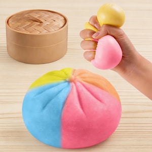 Juguete blando Baozi ultrasuave con degradado arcoíris y pliegues realistas – Viene en una caja vaporera de bambú