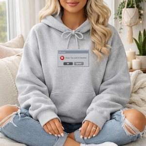 May include: A grey hoodie with a drawstring hood and a front pocket. The hoodie displays a small graphic on the chest, resembling a computer error message, with the text "Error: Too cool to function."