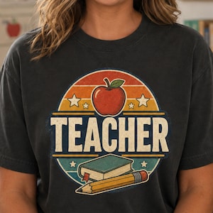Close-up of a Pepper teacher shirt showing the vintage distressed TEACHER graphic with apple, book, pencil and retro striped background.