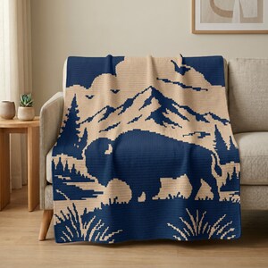 Puede incluir: Una manta de ganchillo azul marino y beige con un dise&ntilde;o de monta&ntilde;a y bisonte, colocada sobre un sof&aacute;. La manta est&aacute; hecha de un material suave y es un elemento de decoraci&oacute;n hogare&ntilde;a acogedor. Las dimensiones de la manta son en cent&iacute;metros.