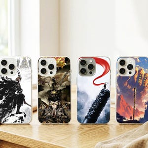 May include: Four phone cases with unique designs. The cases feature illustrations of a warrior, a detailed figure, a person on a staff with a red banner, and a mountain scene. The cases are on a wooden surface.