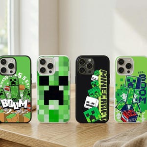 以下が含まれることがあります： Minecraftをテーマにしたデザインの携帯電話ケース4つ。ケースは、ピクセル化されたクリーパーのキャラクターと「BOOM」の文字が入った緑と黒の背景が特徴です。1つのケースには、緑色の「Minecraft」の文字が入っています。