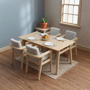 May include: A miniature dining set featuring a light wood rectangular table and four chairs with light grey upholstered seats. The table is set with four white plates, four clear glasses, silver cutlery, and a small bowl containing colourful fruit.