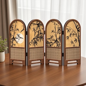 May include: A four-panel folding screen with arched tops, featuring a dark wood frame and a light tan background. Each panel displays black bamboo silhouettes, with one panel showing a full moon. The lower sections have a woven cane texture.