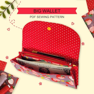 May include: A fabric wallet featuring a red and white polka dot interior flap and a grey exterior patterned with red strawberries. The wallet is open, revealing a zippered compartment and a paper dollar bill. Text reads BIG WALLET PDF SEWING PATTERN.