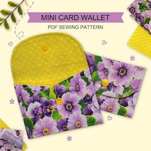 May include: A mini card wallet PDF sewing pattern featuring two fabric wallets with a purple floral print and a yellow polka dot interior lining. Each wallet has a rounded flap secured with a yellow snap button closure. The text reads MINI CARD WALLET.