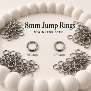 May include: A collection of silver-colored 8mm stainless steel jump rings arranged in piles. The text 8mm Jump Rings and STAINLESS STEEL is visible, along with labels for 16 Gauge and 17 Gauge indicating the thickness of the individual metal rings.