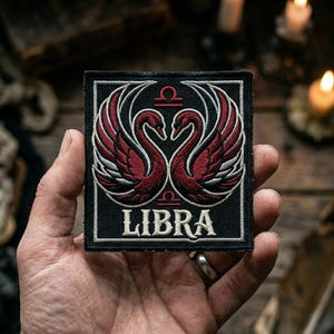 May include: Black square patch featuring a design of two swans facing each other, with red and white detailing. The word "LIBRA" is printed in white at the bottom. The patch includes the Libra zodiac symbol.