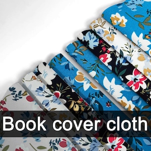 Puede incluir: Una colección de tela floral para cubiertas de libros en varios colores, incluyendo azul, blanco y negro. La tela presenta un patrón repetido de flores y hojas. El texto "Book cover cloth" se muestra en la parte inferior de la imagen.