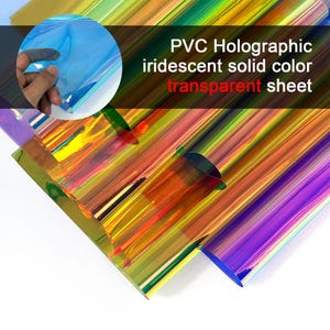 Puede incluir: Una lámina transparente de PVC holográfico iridiscente de color sólido con una superficie lisa y reflectante. El material muestra un espectro de colores cambiantes que incluyen azul, amarillo, naranja y morado. El texto en la imagen dice: PVC Holographic iridescent solid color transparent sheet.