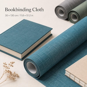 Può includere: Tela per rilegatura color verde acqua con finitura testurizzata, presentata come rotolo e foglio piatto. Il testo recita Bookbinding Cloth 30 x 130 cm / 11.8 x 51.2 in. Sono visibili rotoli aggiuntivi in grigio e verde e due libri rilegati.