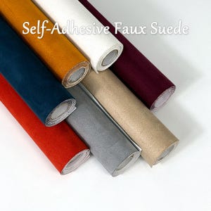 May include: Seven rolls of self-adhesive faux suede fabric in various colors including red, dark blue, mustard yellow, white, burgundy, grey, and beige. The text "Self-Adhesive Faux Suede" is printed in white across the top of the image.