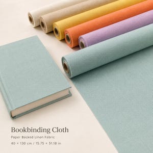 Könnte beinhalten: Eine Sammlung von papierkaschierten Leinen-Buchbindestoffrollen in Creme, Beige, Gelb, Orange, Lavendel und Hellblau sowie ein hellblauer Buchdeckel. Der Text lautet: Bookbinding Cloth, Paper Backed Linen Fabric, 40 x 130 cm / 15.75 x 51.18 in.