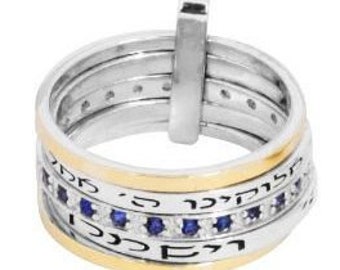 May include: A silver and gold ring with a Hebrew inscription and blue sapphires. The ring is made up of four bands.