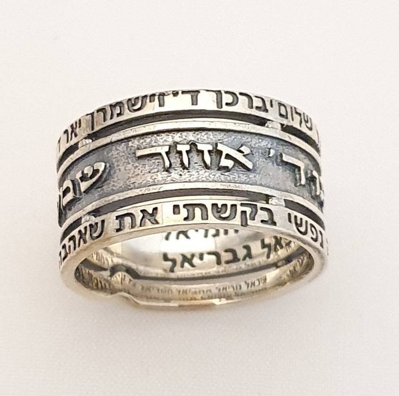 May include: A silver ring with Hebrew text inscribed around the band. The text reads "Shema Yisrael Adonai Eloheinu Adonai Echad" which translates to "Hear O Israel, the Lord our God, the Lord is One."