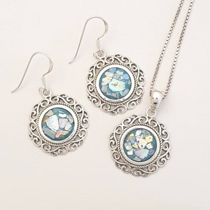 May include: A set of silver earrings and a necklace with a round pendant. Each piece features a blue and green mosaic design in a silver filigree frame.
