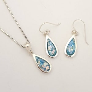 May include: A silver necklace and earrings set with teardrop-shaped pendants featuring blue and white mosaic glass.