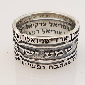 May include: A silver ring with Hebrew text inscribed around the band. The text reads "מיאל עזריאל תמניאל", "חסדיאל צדקיאלרי", "שמרך יאר די פניו אליך וית", "אוריאל רפא", "שבוע לשרץ", and "IN שאהבה נפשי נט.איה".