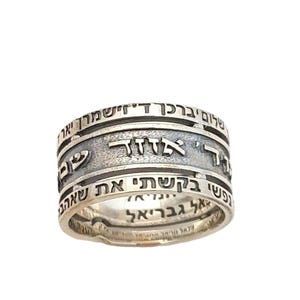 May include: A silver ring with three bands, each inscribed with Hebrew text. The text on the top band reads "Atah Kedoshah", the middle band reads "Atah Gedolah", and the bottom band reads "Atah Kadosh".