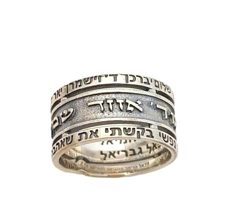 May include: A silver ring with three bands, each inscribed with Hebrew text. The text on the top band reads "Atah Kedoshah", the middle band reads "Atah Gedolah", and the bottom band reads "Atah Kadosh".