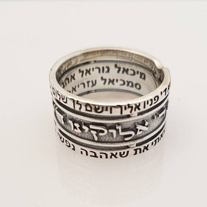 May include: A silver ring with Hebrew text inscribed around the band. The text reads: "מיכאל גוריאל אה סמכיאל עזריא די פניו אליך וישם לך שלום בןלוקינו אתי את שאהבה נפשי"