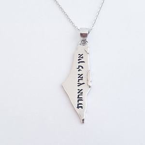 Puede incluir: Collar de plata con un colgante con forma del contorno de Israel. El colgante tiene escritura en hebreo.