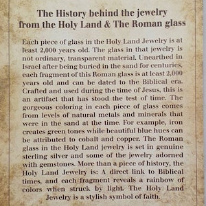 May include: A printed card with text describing the history of Holy Land jewelry and Roman glass. The text is in black on a beige background with decorative corner flourishes. The card details the age and origin of the glass.