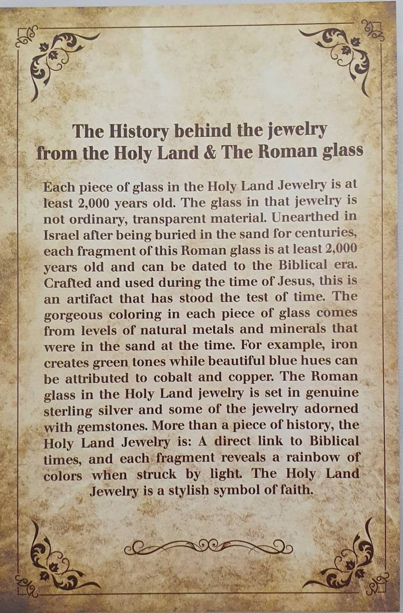May include: A printed card with text describing the history of Holy Land jewelry and Roman glass. The text is in black on a beige background with decorative corner flourishes. The card details the age and origin of the glass.