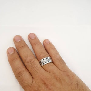 May include: A silver ring with three bands, each inscribed with Hebrew text.