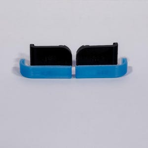 Puede incluir: Dos conjuntos de componentes, cada uno formado por un soporte negro en forma de L y una pieza de pl&aacute;stico azul brillante curvada. Los soportes negros presentan un borde superior plano y un lado redondeado, mientras que las piezas azules son lisas.
