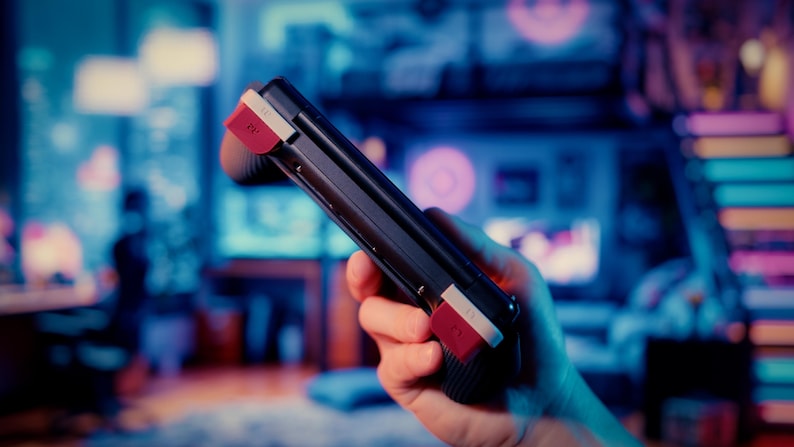 May include: A black handheld gaming controller featuring two prominent red shoulder buttons with white L1 and R1 labels. The device has a textured grip surface on the sides and a sleek, dark frame, designed for portable gaming interaction.
