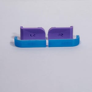 Puede incluir: Un juego de cuatro extensiones para gatillos de mando que consta de dos piezas moradas etiquetadas como L2 y R2, y dos piezas curvas azules a juego. Estos accesorios de pl&aacute;stico para videojuegos est&aacute;n dise&ntilde;ados para acoplarse a los gatillos.
