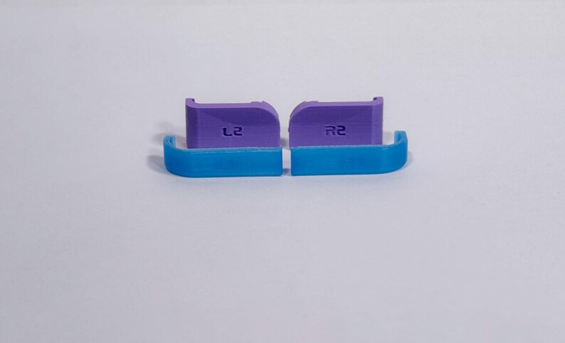 Puede incluir: Un juego de cuatro extensiones para gatillos de mando que consta de dos piezas moradas etiquetadas como L2 y R2, y dos piezas curvas azules a juego. Estos accesorios de pl&aacute;stico para videojuegos est&aacute;n dise&ntilde;ados para acoplarse a los gatillos.