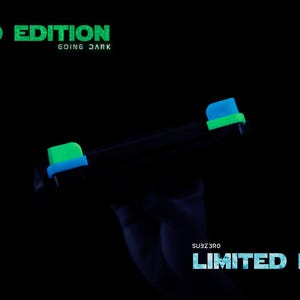 Puede incluir: Un mando de juego negro con detalles en verde ne&oacute;n y azul brillante en los botones superiores. El texto LIMITED EDITION GOING DARK aparece en verde en la parte superior, y SUBZERO LIMITED EDITION est&aacute; impreso en azul abajo a la derecha.