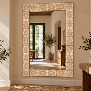 May include: A large rectangular wall mirror featuring a decorative frame composed of square tiles. Each tile displays a repeating intricate floral pattern in shades of tan, beige, and white, creating a symmetrical border around the reflective glass.