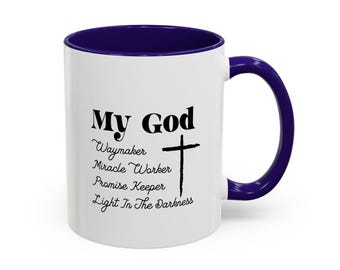 May include: A white ceramic mug with a deep purple interior and handle. The exterior features black text that reads My God, Waymaker, Miracle Worker, Promise Keeper, Light In The Darkness, accompanied by a black cross graphic on the right side.