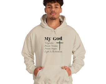 May include: A sand-colored hooded sweatshirt featuring black text that reads My God, Waymaker, Miracle Worker, Promise Keeper, Light In The Darkness, accompanied by a black cross graphic centered on the chest area of the garment.