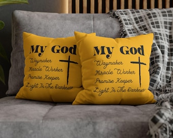 May include: Two square mustard yellow throw pillows featuring black text that reads My God Waymaker Miracle Worker Promise Keeper Light In The Darkness, accompanied by a black cross graphic printed on the front of each pillow.