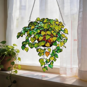 May include: A stained glass hanging plant featuring numerous heart-shaped leaves in shades of green and yellow, suspended by metal chains. The piece measures 20.32 cm in height and 20.32 cm in width, showcasing a vibrant, multi-toned foliage design.