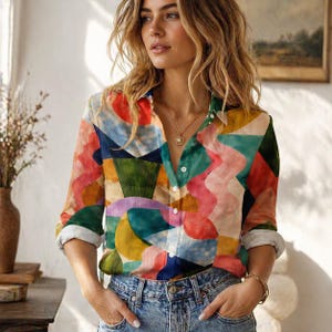 Pode incluir: Uma camisa colorida com botões e um design abstrato vibrante. A camisa apresenta uma mistura de formas geométricas e onduladas em tons de vermelho, azul, verde, amarelo e rosa. A camisa de manga comprida é combinada com jeans azuis.