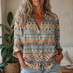 May include: A collared button-down shirt with a V-neck, featuring a geometric pattern in shades of brown, tan, blue, and white. The shirt has three-quarter sleeves and is worn with blue jeans. The overall style is casual and bohemian.