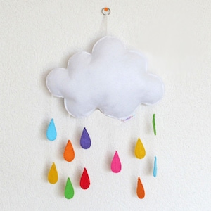 May include: A white felt cloud mobile with rainbow coloured felt raindrops hanging from it.